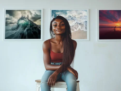 Photographie de l'artiste Inès Konaté assise devant trois de ses œuvres
