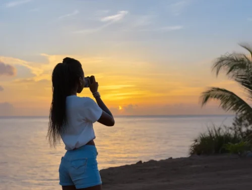 Photographie de l'artiste Inès Konaté prenant une photo d'un coucher de soleil sur la mer